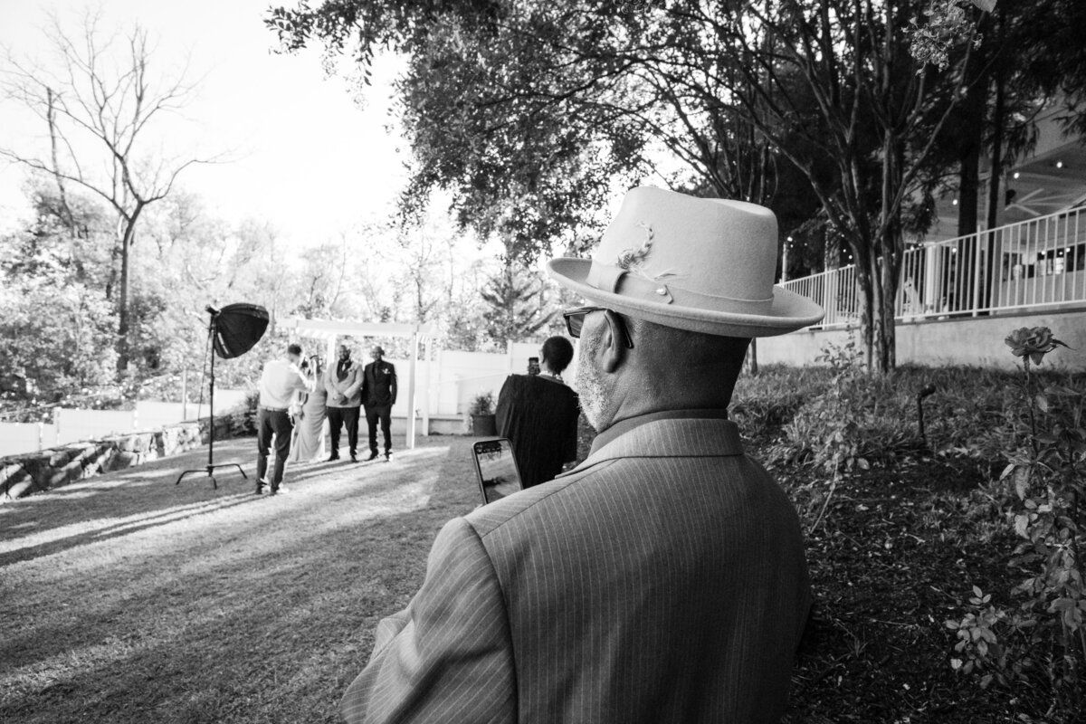 Guest in a hat watching the ceremony — black and white documentary Maryland wedding photograph